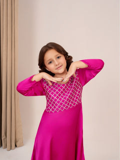 Young girl wearing a pink traditional outfit with a geometric design on a neutral background