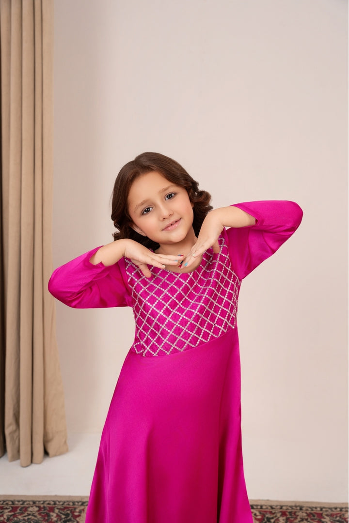 Young girl wearing a pink traditional outfit with a geometric design on a neutral background